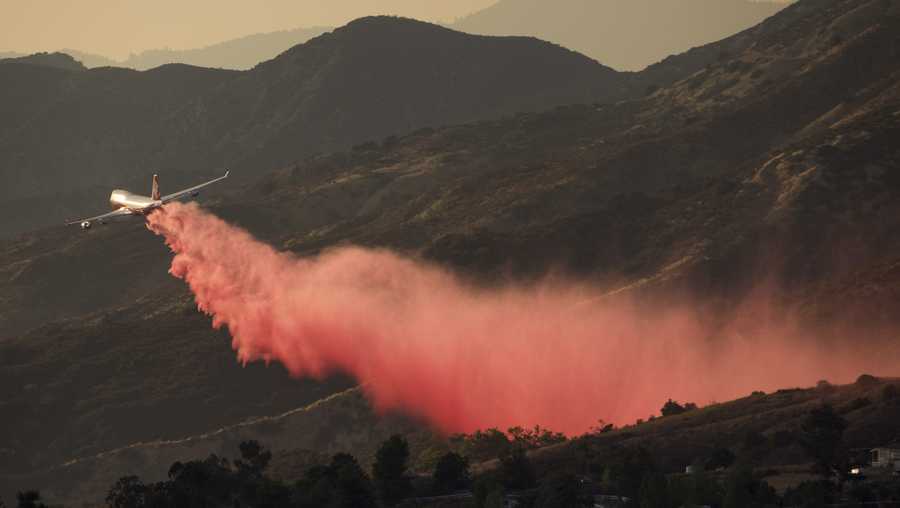 An air tanker drops retardant at a wildfire burns at a hillside in Yucaipa, Calif., Saturday, Sept. 5, 2020. Three fast-spreading wildfires sent people fleeing and trapped campers in one campground as a brutal heat wave pushed temperatures above 100 degrees in many parts of California. (AP Photo/Ringo H.W. Chiu)