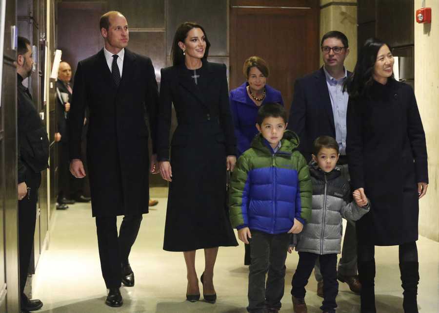 Boston Mayor Michelle Wu, right, and her family show photos of the Queen Elizabeth II's visit in 1976, during the visit of Britain's Prince William and Kate, Princess of Wales, to Boston City Hall on Wednesday, Nov. 30, 2022, in Boston. The Prince and Princess of Wales are making their first overseas trip since the death of Queen Elizabeth II in September. (Nancy Lane/The Boston Herald via AP, Pool)