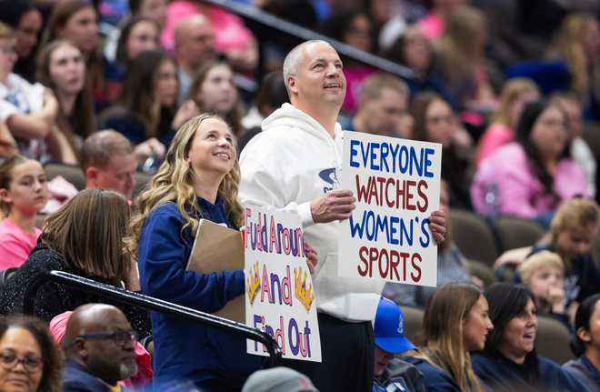 Fans hold up signs in support of UConn&amp;apos;s Azzi Fudd and women&amp;apos;s sports as UConn plays against Creighton during the second half of an NCAA college basketball game.