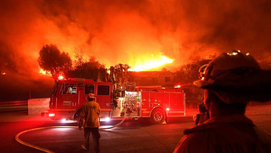 Los Angeles County firefighters look on as the Woolsey Fire rages behind a house in the West Hills neighborhood on Nov. 9, 2018 in Los Angeles.