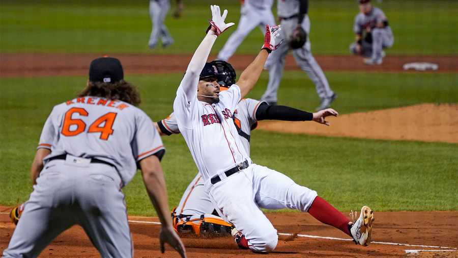 Boston Red Sox's Xander Bogaerts scores on a double by J.D. Martinez as Baltimore Orioles starting pitcher Dean Kremer (64) backs up the throw during the third inning of a baseball game in Boston, Wednesday, Sept. 23, 2020, at Fenway Park. (AP Photo/Charles Krupa)