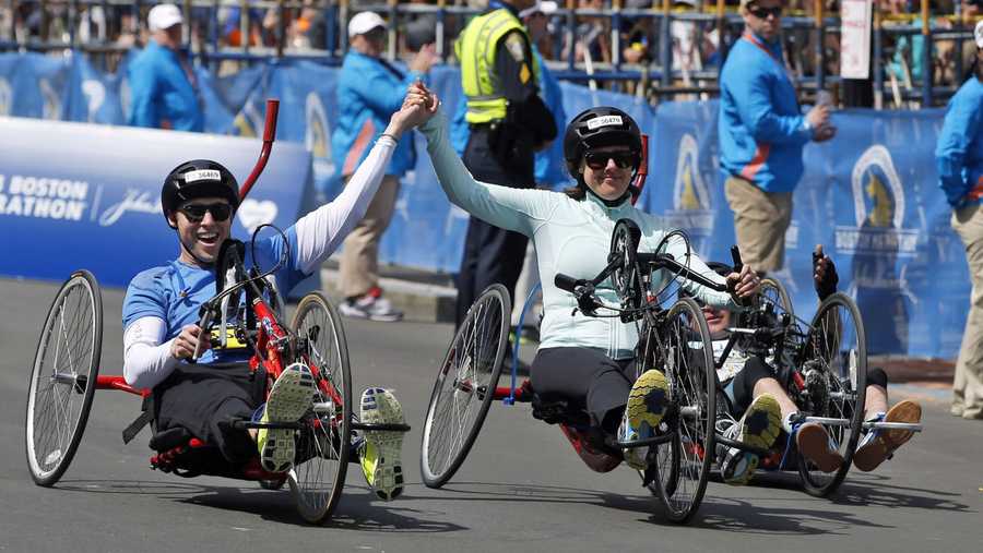 Boston Marathon husband and wife bombing survivors Patrick Downes and Jessica Kensky, who each lost a leg in last year's bombings, roll across the finish line in the 118th Boston Marathon Monday, April 21, 2014 in Boston.