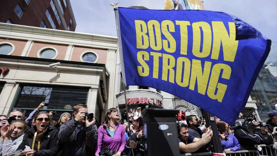 Race fans with a "Boston Strong" flag cheer for competitors near the finish line of the 118th Boston Marathon, Monday, April 21, 2014, in Boston.