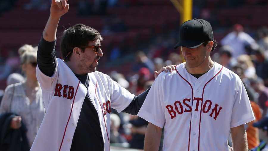 Boston Marathon bombing survivor Jeff Bauman, left, walks with actor Jake Gyllenhaal before throwing out the first pitch before a baseball game between the Boston Red Sox and the Toronto Blue Jays at Fenway Park, Monday, April 18, 2016, in Boston. Gyllenhaal is playing Bauman in a movie called Stronger. 