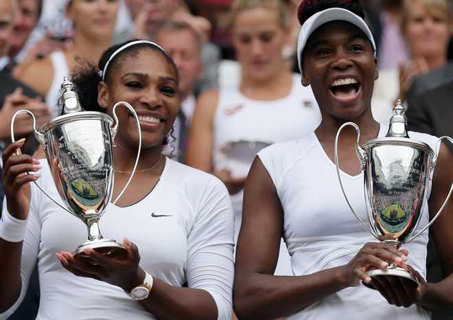Serena Williams, left, and Venus Williams of the U.S hold their trophies after winning the women's doubles final against Yaroslava Shvedova of Kazahkstan and Timea Babos of Hungary on day thirteen of the Wimbledon Tennis Championships in London, July 9, 2016.