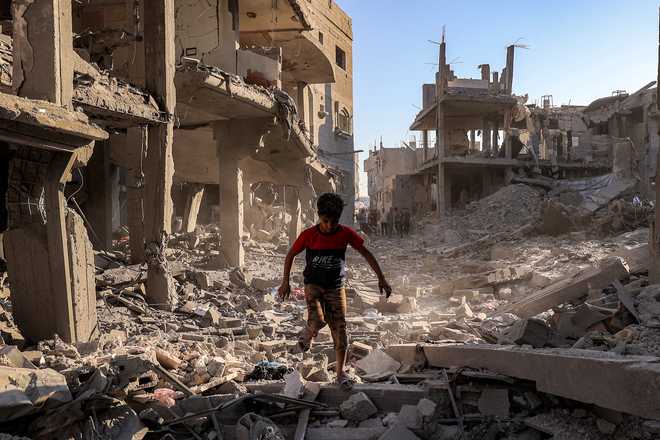 A boy walks through the rubble of a building that was destroyed following Israeli bombardment after an evacuation order, at the Maghazi camp for Palestinian refugees in the central Gaza Strip on June 12, 2026.