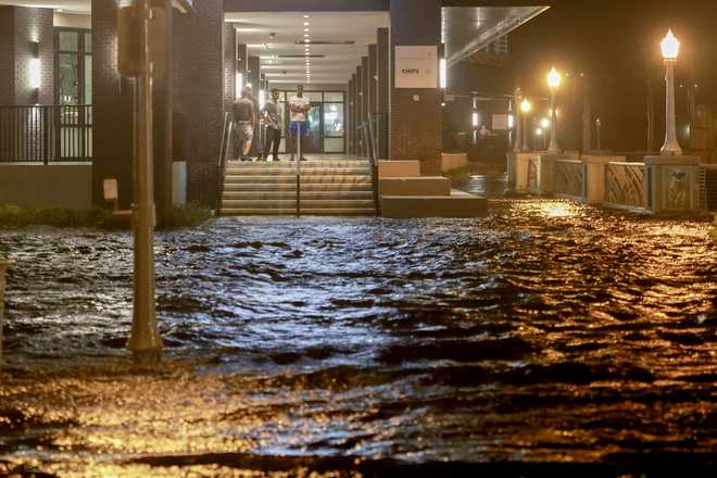 FORT MYERS BEACH, FLORIDA - OCTOBER 09: People look out at surge waters flooding the street from their building after Hurricane Milton came ashore in the Sarasota area on October 09, 2024, in Fort Myers, Florida. People are waiting to assess the damage after the Cat 3 hurricane came ashore. (Photo by Joe Raedle/Getty Images)
