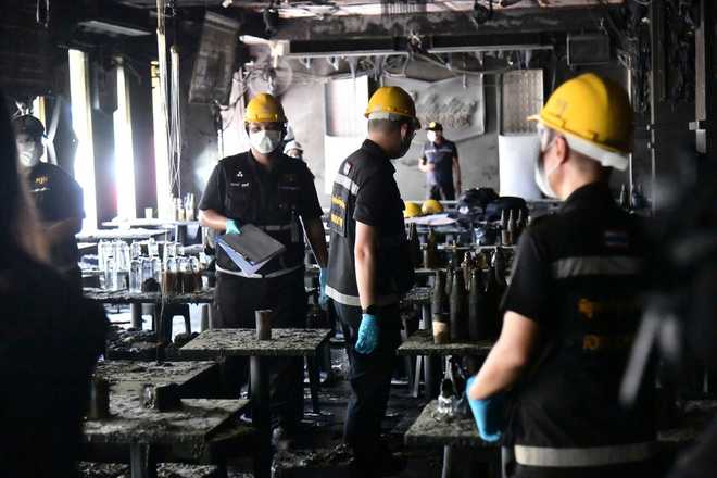 In this handout photo released by Bangkok Metropolitan Administration, forensic police officers inspect the site of a fire in Bangkok, Thailand, Monday, July 13, 2026.