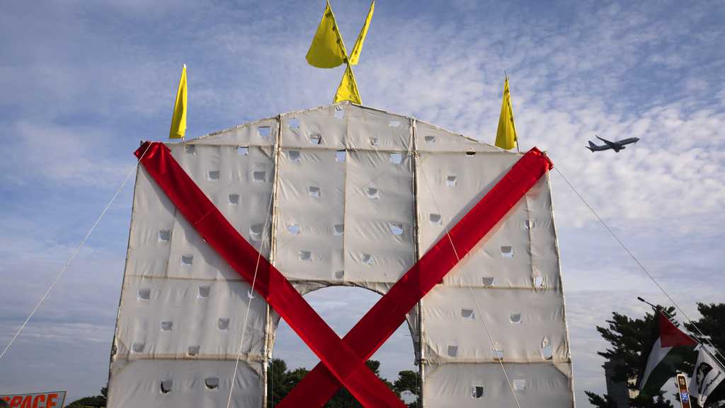 Photo: ksbw.com A plane flies over an anti-arch structure lifted up by demonstrators at Memorial Circle to protest the proposed Triumphal