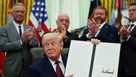 President Donald Trump holds up a signed executive order in the Oval Office of the White House, Saturday, April 18, 2026, in Washington. (AP Photo/Julia Demaree Nikhinson)