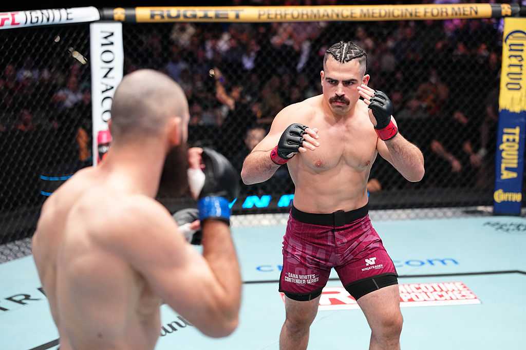 Luis Hernandez facing an opponent in the cage, maroon shorts, mustache
