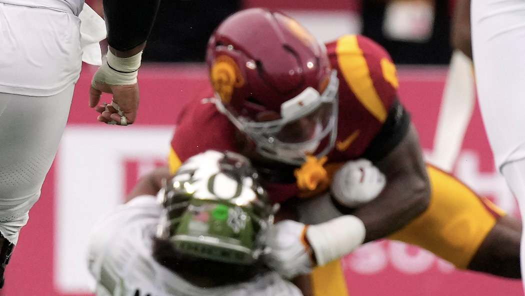 Photo: wvtm13.com Oregon quarterback Dante Moore, center bottom, takes a hard tackle by Southern California inebacker Desman Stephens II