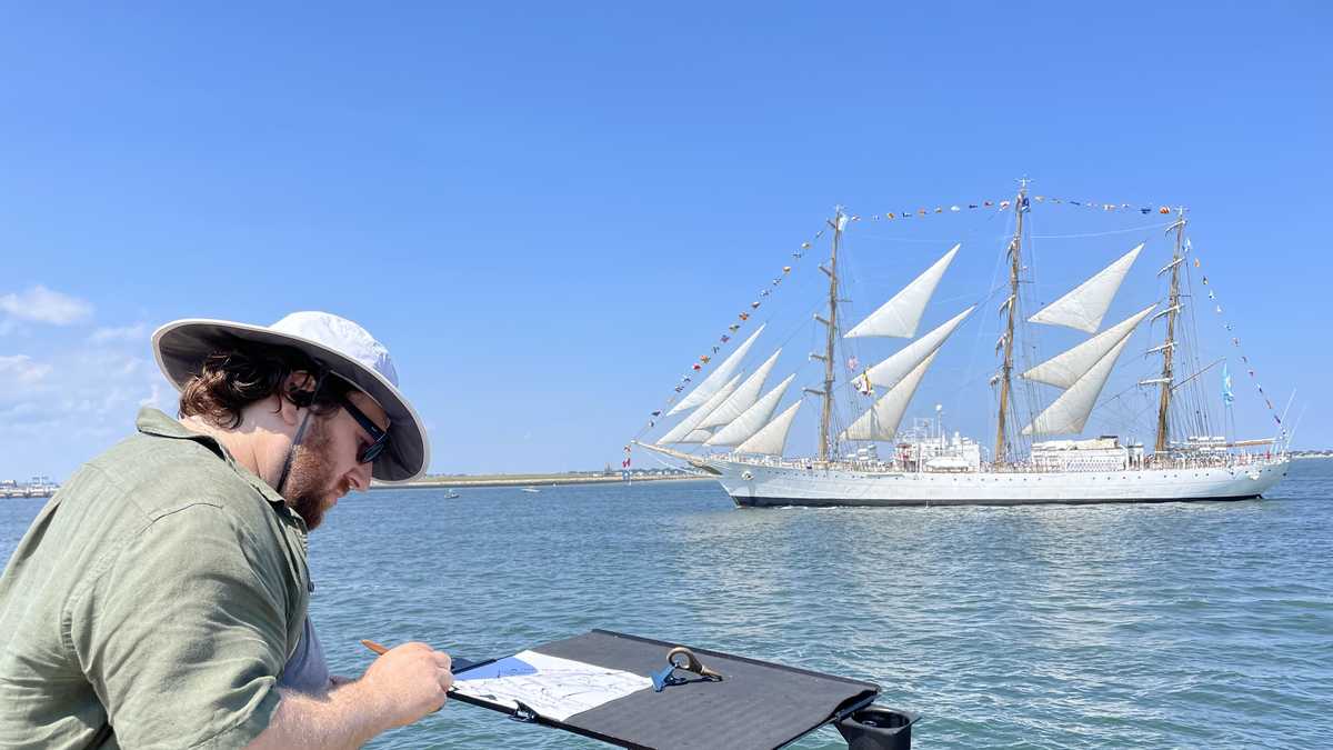 Artist works on Castle Island as Parade of Sail goes by