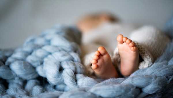 Foot of newborn baby on warm blanket
