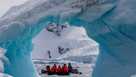 Tourists in a zodiac exploring an iceberg arch in Cierva