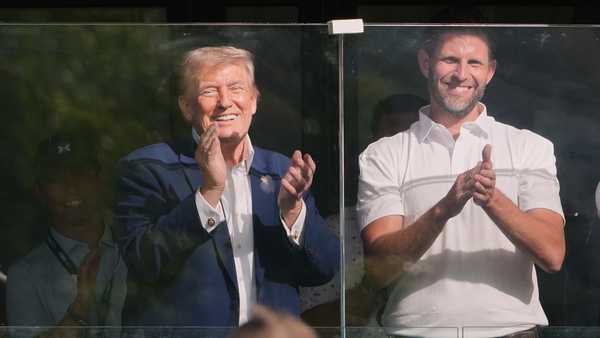 Golfer Bryson DeChambeau, foreground, doffs his hat to President Donald Trump and Eric Trump during the Maaden LIV Golf Virginia tournament at Trump National Golf Club, Saturday, May 9, 2026, in Sterling, Va.