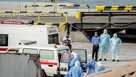 Health personnel returning from the cruise ship MV Hondius are seen at the port of Praia, Cape Verde, as people wearing hazmat suits are helped into an ambulance on May 6.