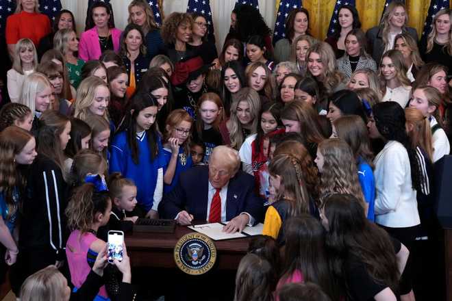 WASHINGTON, DC - FEBRUARY 05: U.S. President Donald Trump joined by women athletes signs the “No Men in Women’s Sports” executive order in the East Room at the White House on February 5, 2025 in Washington, DC. The executive order, which Trump signed on National Girls and Women in Sports Day, prohibits transgender women from competing in women’s sports and is the third order he has signed that targets transgender people. (Photo by Andrew Harnik/Getty Images)