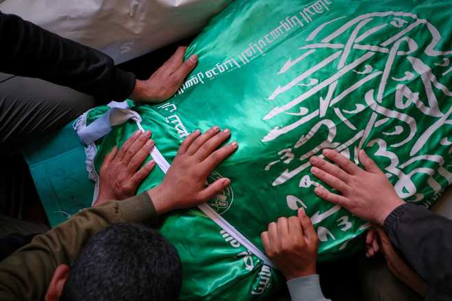 Palestinians place their hands on the body of Izz al-Din al-Haddad, the leader of Hamas&amp;#39; Qassam Brigades, draped in a Hamas flag during his funeral in Gaza City, Saturday, May 16, 2026. (AP Photo/Jehad Alshrafi)