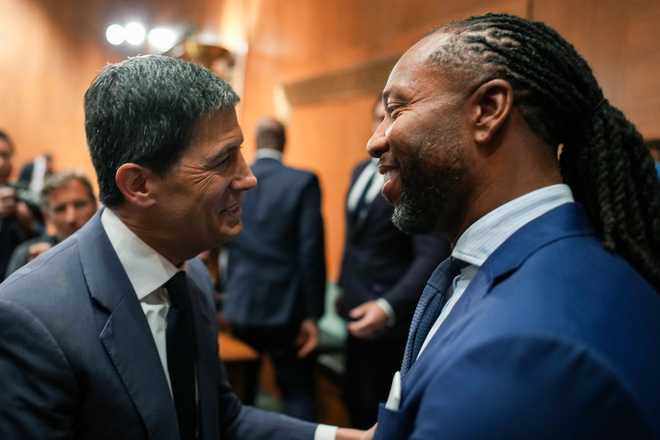 WASHINGTON, DC - APRIL 21: Kevin Warsh (L), U.S. President Donald Trump's nominee for Chair of the Federal Reserve, greets former NFL player Larry Fitzgerald Jr. (R) during his Senate Committee on Banking, Housing, and Urban Affairs confirmation hearing in the Dirksen Senate Office Building on April 21, 2026 in Washington, DC. President Trump nominated Warsh, a former member of the Federal Reserve Board of Governors, to replace Jerome Powell amid bipartisan concerns over the Justice Department's criminal investigation into the central bank’s current leader. (Photo by Andrew Harnik/Getty Images)