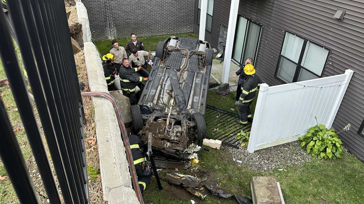 Driver injured after car crashes through fence, lands on roof of ...