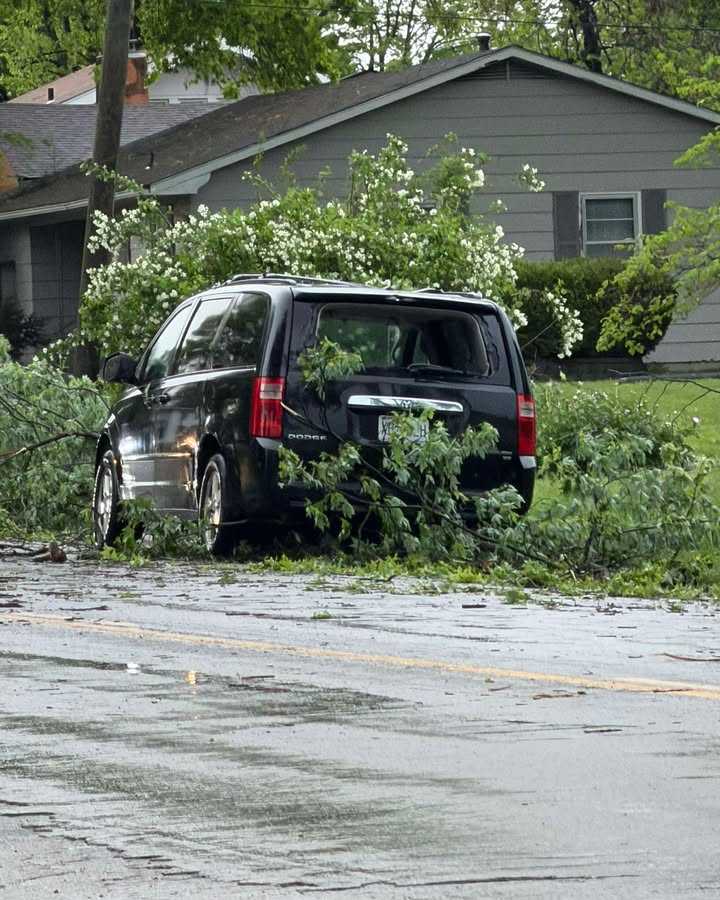 A tree is down and seemingly cracked the back window of a van in Slater, Missouri, after tornado-warned storms on April 27, 2026.
