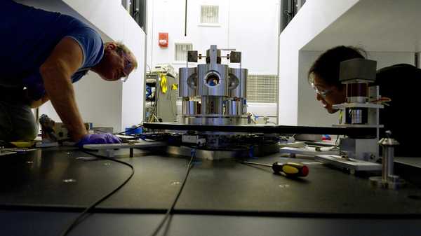 Scientists Stephan Schlamminger (left) and Vincent Lee examine the torsion balance they used to measure the gravitational constant, Big G.