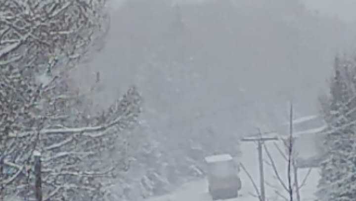 Several trucks stuck, blocking road, as snow falls across the Maine mountains