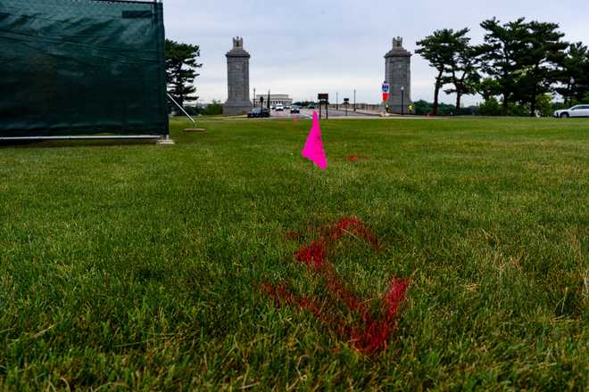 Flags are placed as workers survey the Memorial Circle, where President Donald Trump has proposed building an arch to commemorate the United States' 250th anniversary, Monday, May 11, 2026, in Washington. (AP Photo/Alex Brandon)