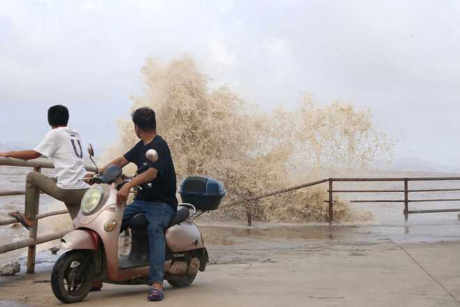 People look on as large waves crash against the coast amid weather patterns from approaching Typhoon Bavi in Wenling city, Taizhou, China's eastern Zhejiang province on July 10, 2026. (Photo by CN-STR / AFP via Getty Images) / China OUT