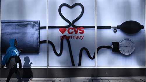 CVS will change the way it prices drugs. A woman walks past a CVS Pharmacy in Washington, DC, in 2022.