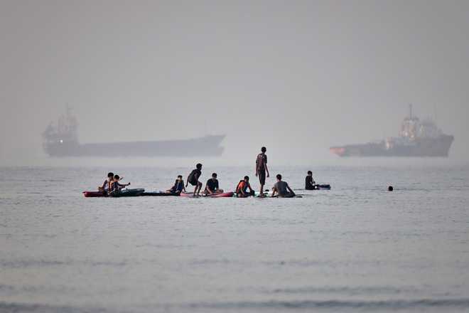 People gather on paddleboards in shallow water as cargo and service vessels are anchored in the Strait of Hormuz off Bandar Abbas, Iran, Monday, June 1, 2026.