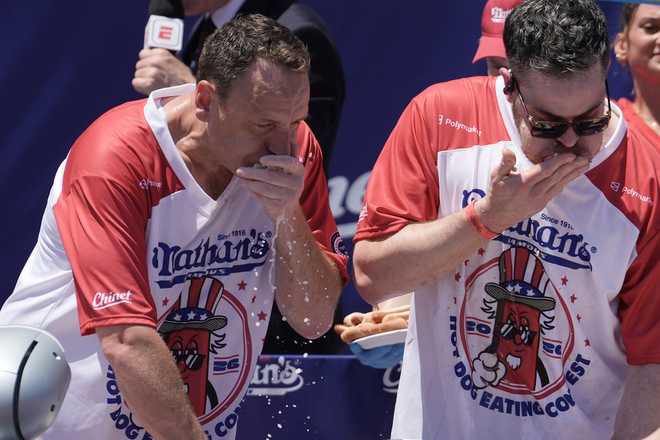 Joey Chestnut and other competitive eaters consume hot dogs during the 2026 Nathan's Famous Fourth of July hot dog eating contest at Coney Island in the Brooklyn borough of New York, Saturday, July 4, 2026. (AP Photo/Anna Connors)