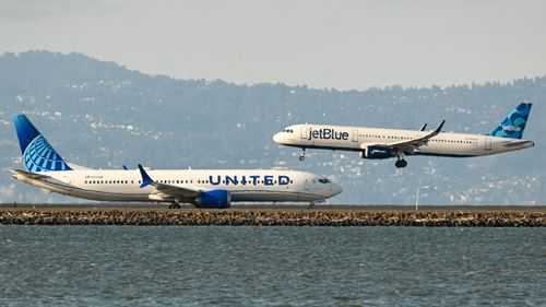 A United Airlines plane prepares for takeoff as a JetBlue plane lands at San Francisco International Airport in 2023.
