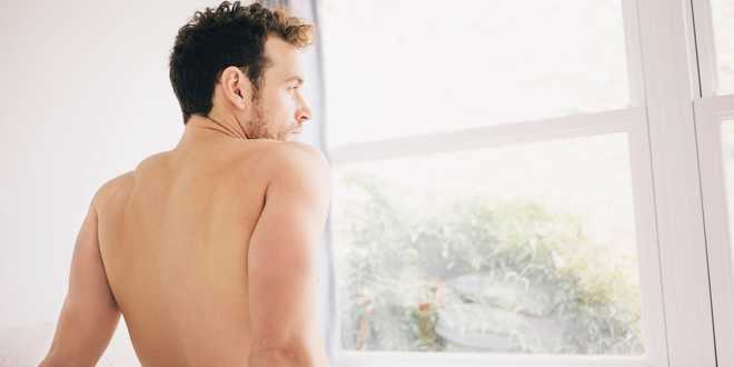 Naked&#x20;man&#x20;looking&#x20;out&#x20;of&#x20;window