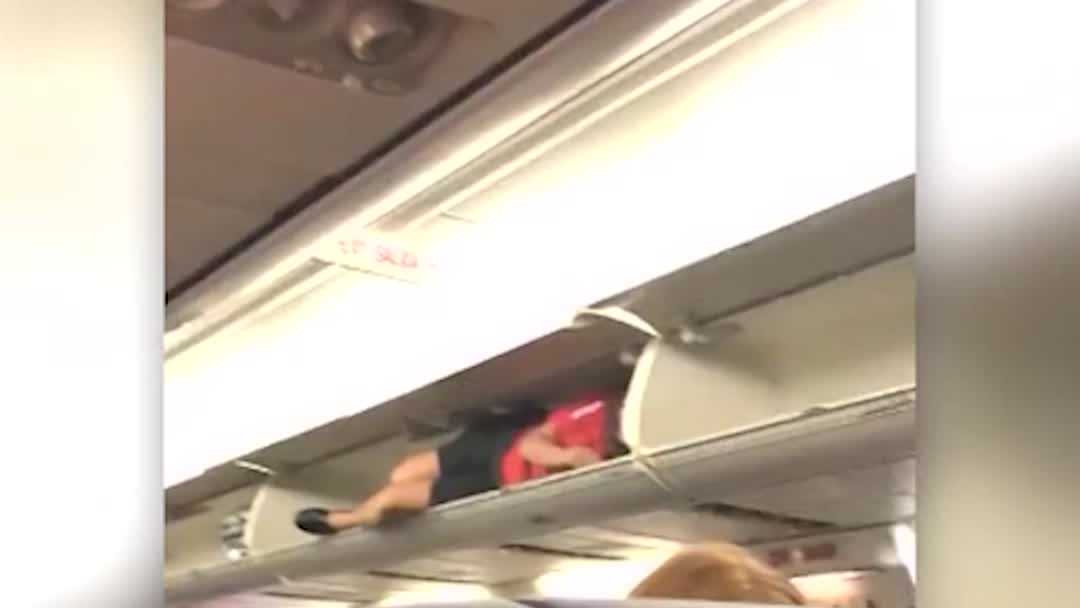 Southwest Airlines flight attendant crawls into overhead compartment as
